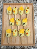 Handcrafted honey bear and bumblebee cakesicles displayed on a wooden tray